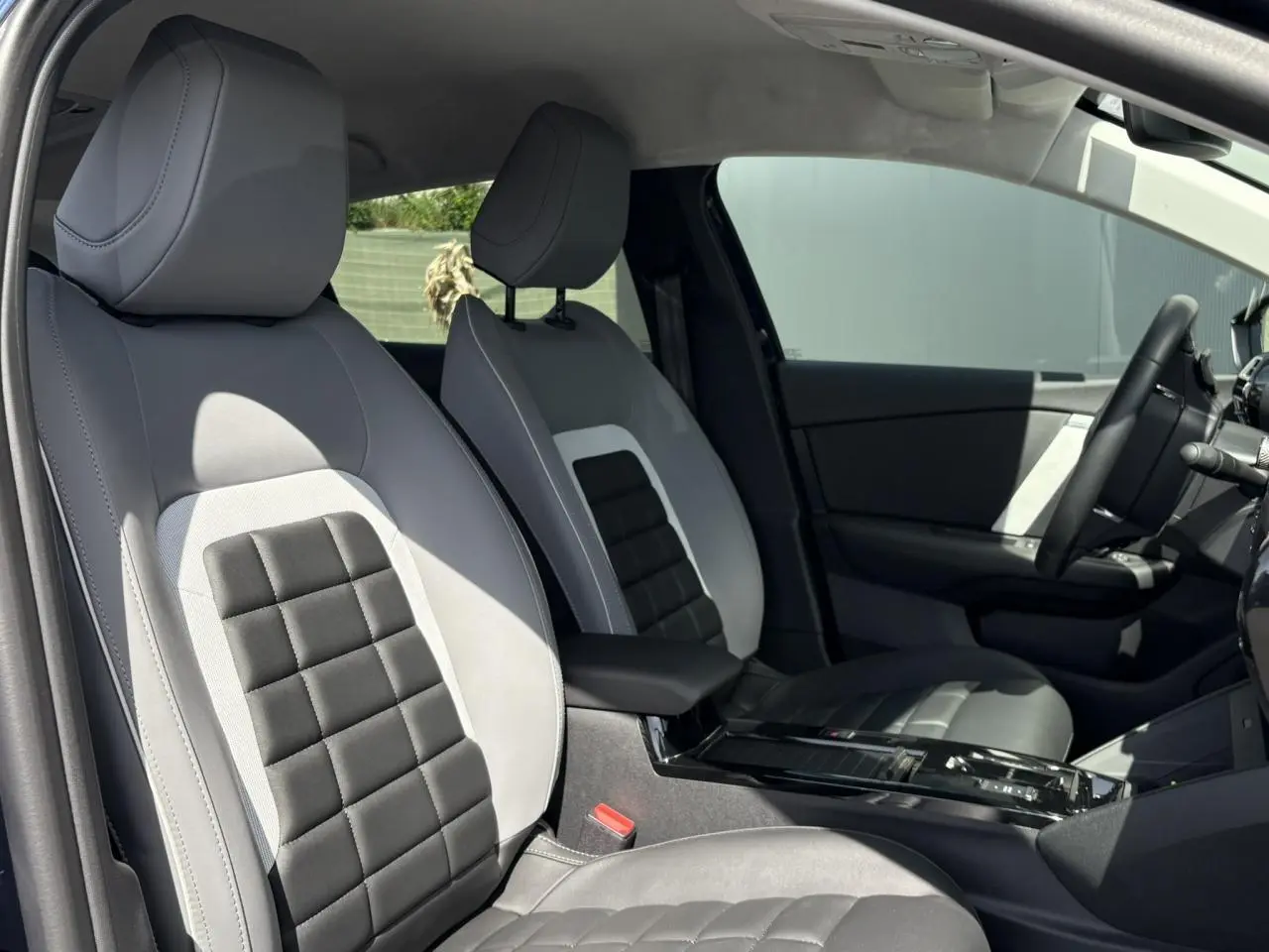Vue intérieure côté gauche des sièges avant gris clair et noir de la Citroën C4 Hybrid 2025 avec accoudoir central.