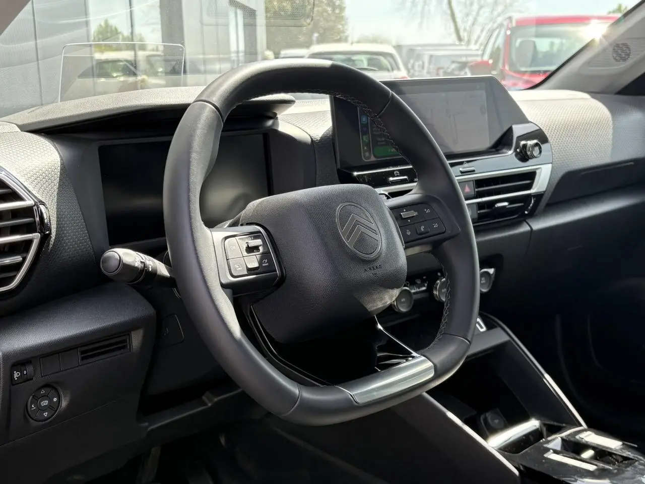 Vue intérieure centrée sur le volant cuir noir et le tableau de bord moderne du Citroën C4 Hybrid 2025.