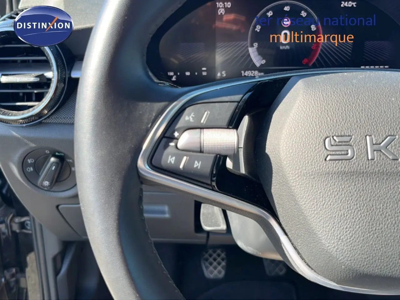 Gros plan sur le volant noir et le tableau de bord digital d'une Skoda Fabia 2025, avec commandes multifonctions visibles.