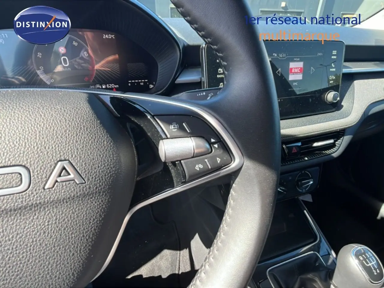 Vue intérieure centrée sur le volant et le tableau de bord d’une Skoda Fabia noire avec boîte manuelle et écran tactile.