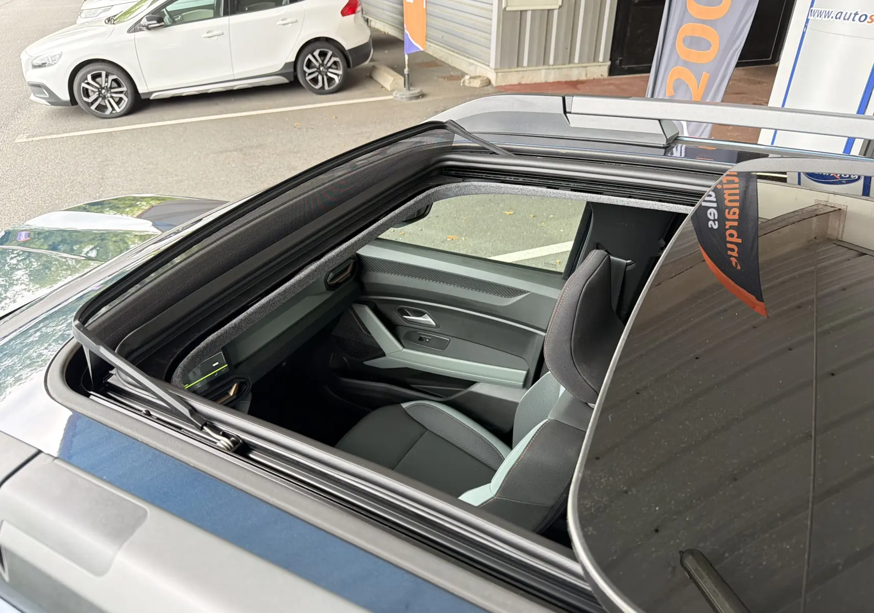 Vue plongeante sur le toit ouvrant panoramique du Dacia Bigster bleu indigo, intérieur avant visible côté droit.