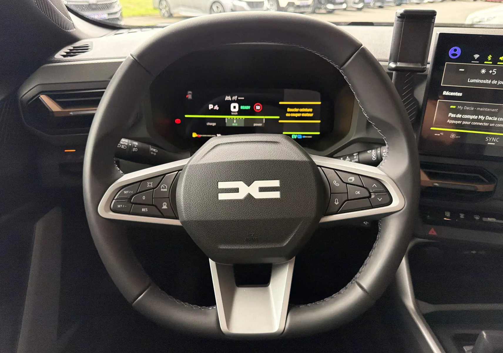 Vue intérieure centrée sur le volant multifonction du Dacia Bigster Hybrid 155, avec tableau de bord numérique et écran tactile.