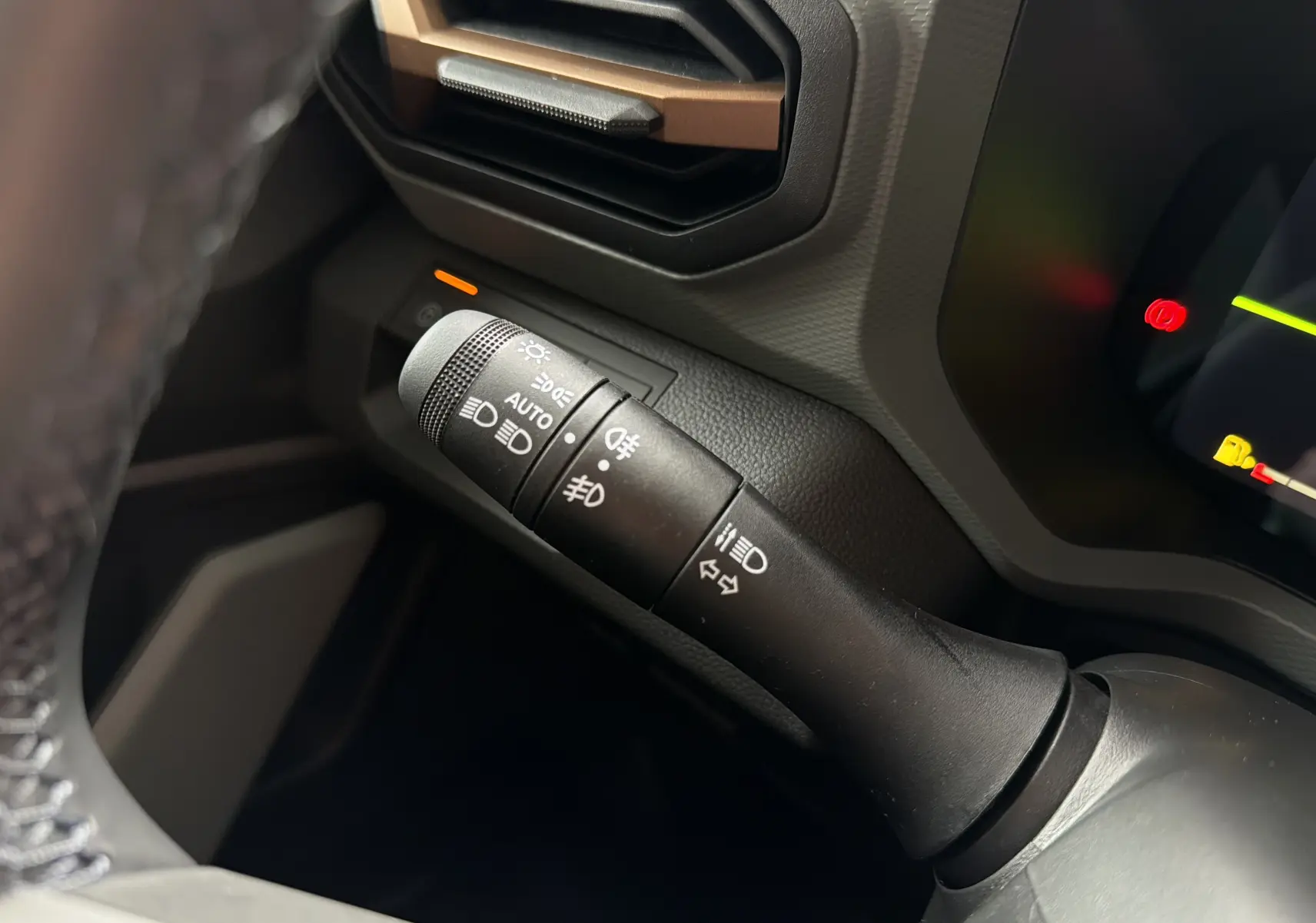 Gros plan sur la commande des feux et clignotants à gauche du volant dans l’habitacle du Dacia Bigster Hybrid 155 Extreme.