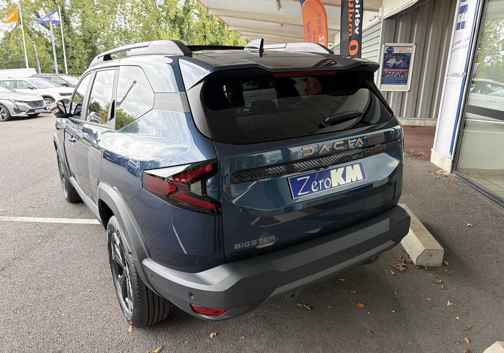 Vue 3/4 arrière droite du Dacia Bigster Hybrid 155 Extreme bleu indigo avec barres de toit et jantes diamantées.