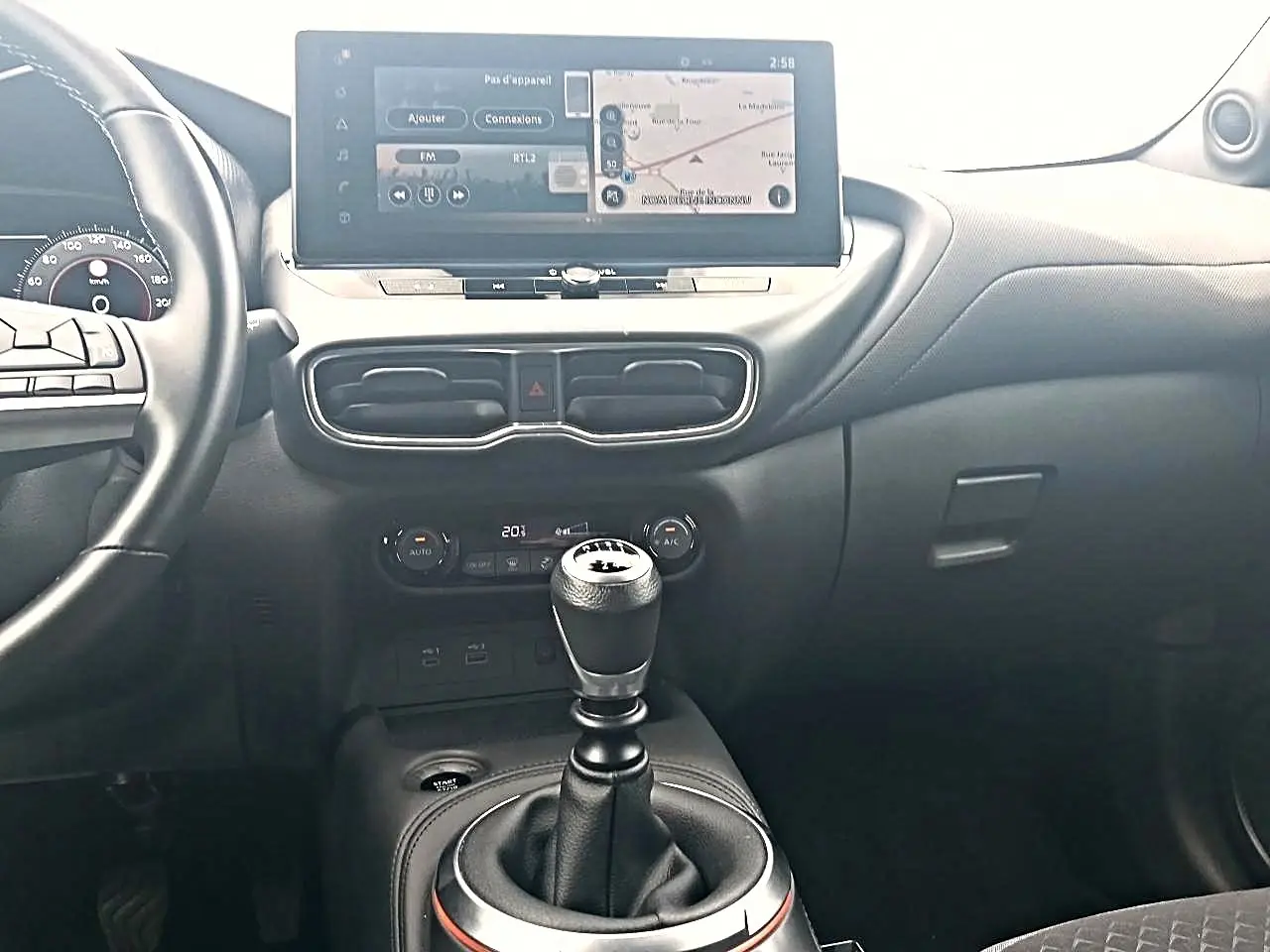 Intérieur du Nissan Juke 2025, vue centrale sur la console avec levier de vitesse manuel et écran tactile couleur.