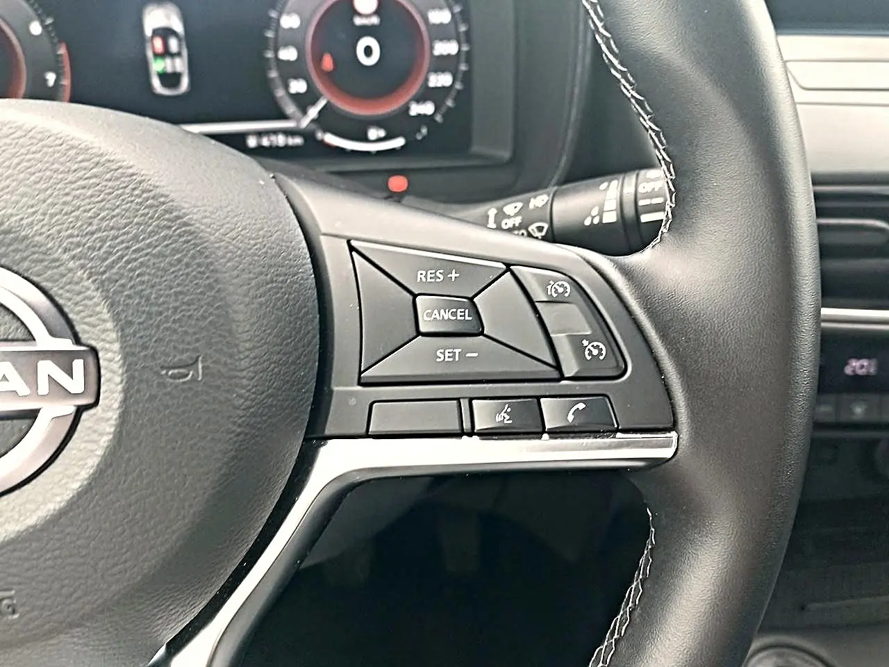 Gros plan sur le volant cuir noir du Nissan Juke 2025, montrant les commandes multifonctions côté droit.
