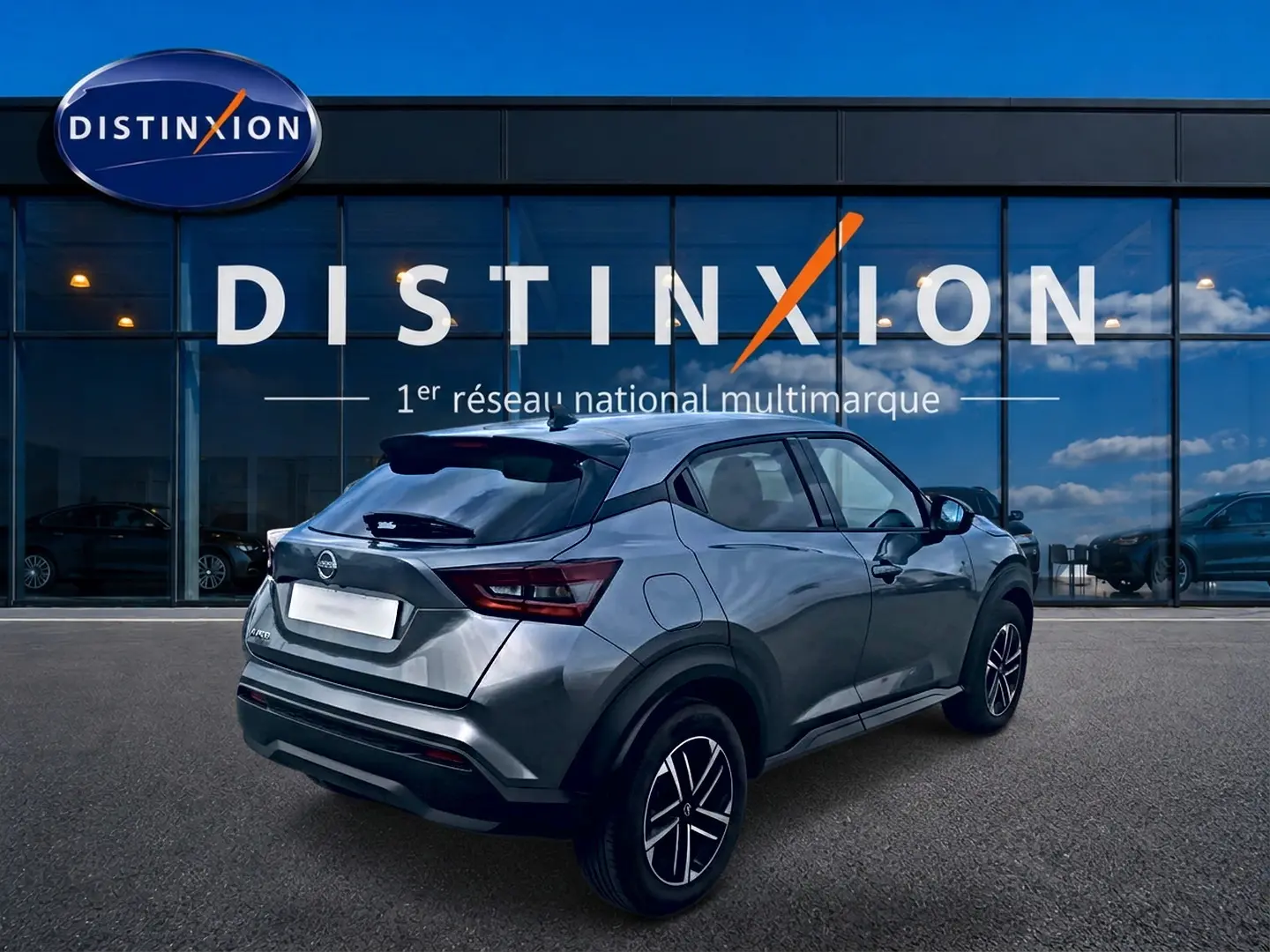 Nissan Juke gris 3/4 arrière droit, avec jantes alu et feux arrière LED, devant une vitrine Distinxion.