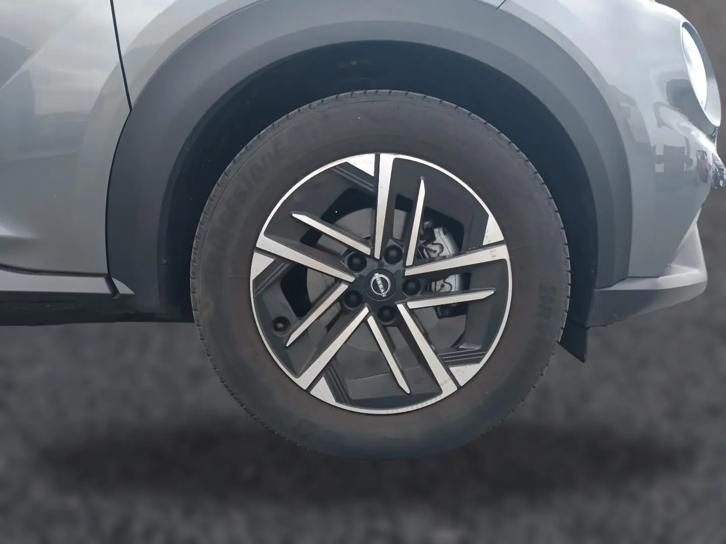 Gros plan sur la roue avant gauche du Nissan Juke gris 2025 avec jante alu au design moderne à branches croisées.