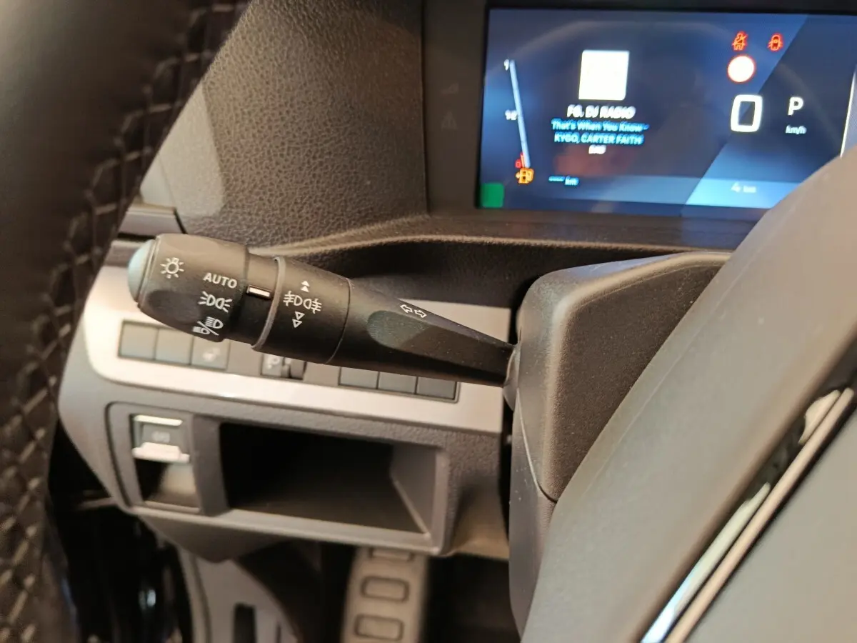 Gros plan sur la manette des phares et clignotants à gauche du volant du Peugeot Expert Fourgon noir, tableau de bord numérique visible.