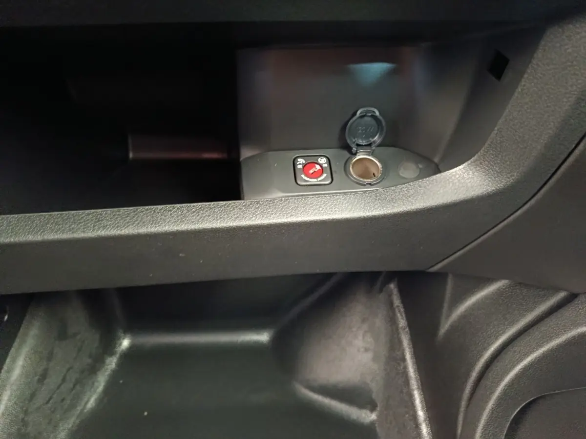 Gros plan sur la prise 12V et le bouton de commande dans le compartiment de rangement intérieur noir du Peugeot Expert Fourgon XL.