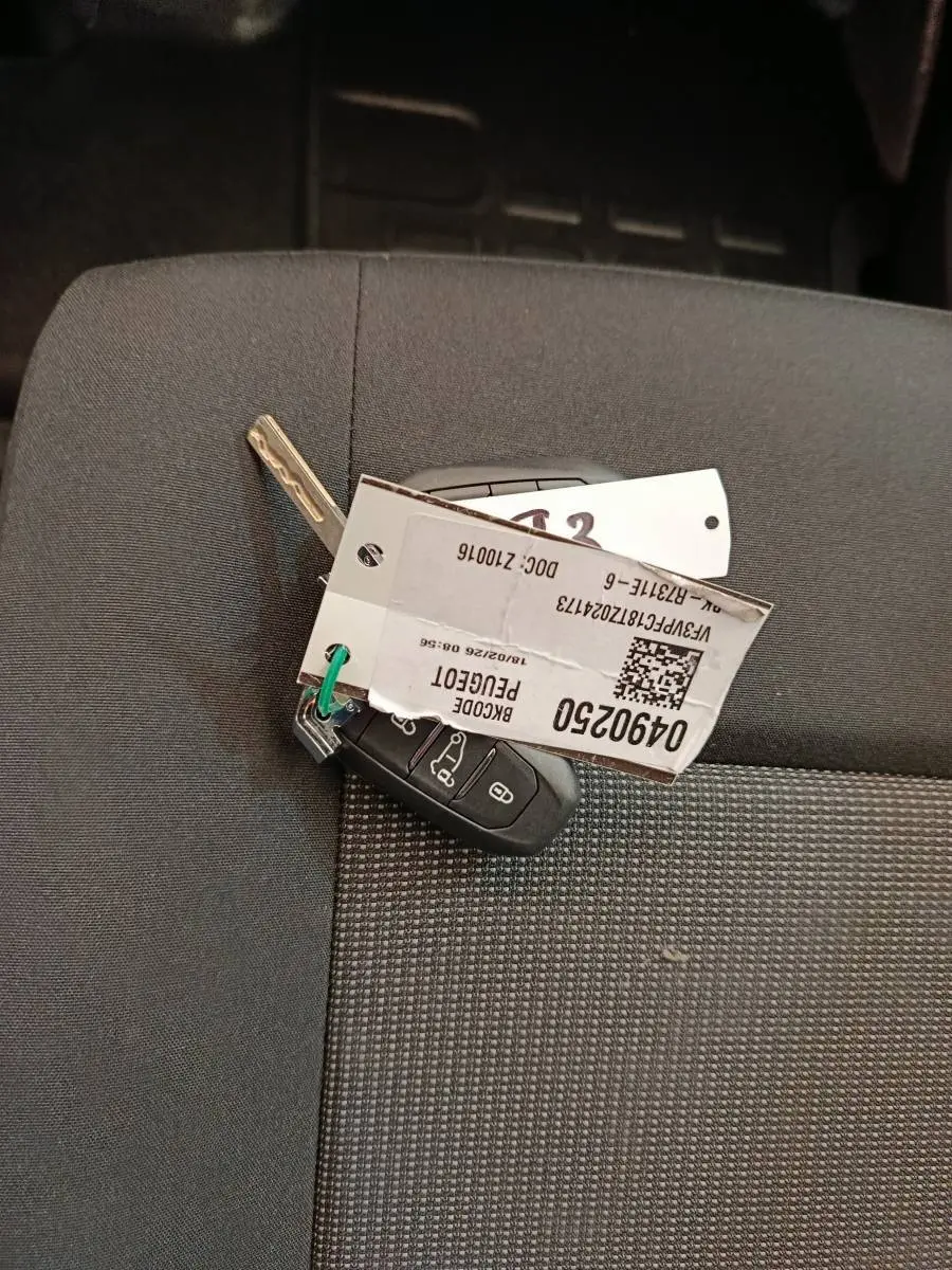 Clé de contact Peugeot Expert Fourgon XL Diesel posée sur un siège tissu gris foncé à motifs.