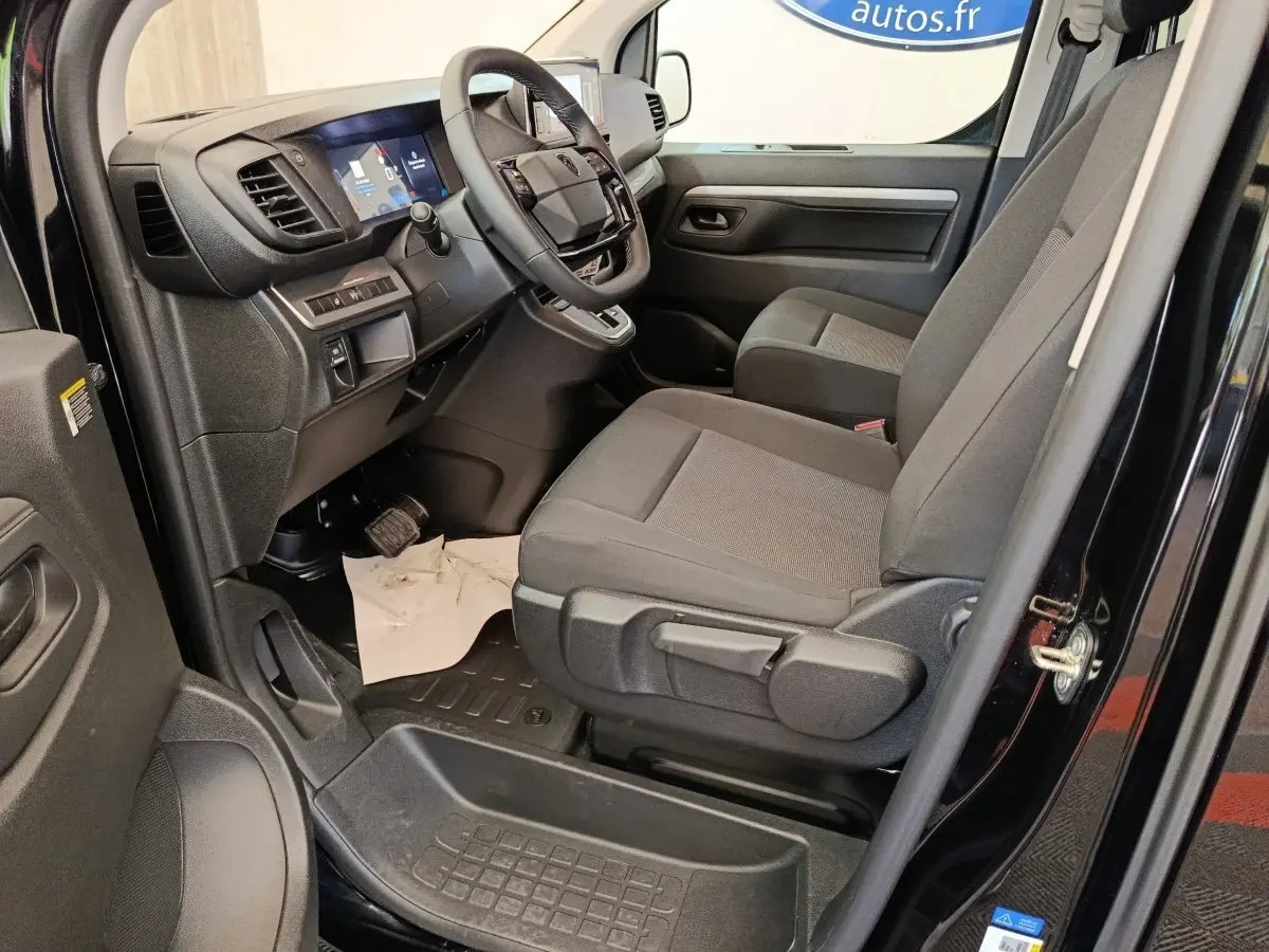 Vue intérieure côté conducteur du Peugeot Expert Fourgon XL noir, montrant le tableau de bord et les sièges avant gris.