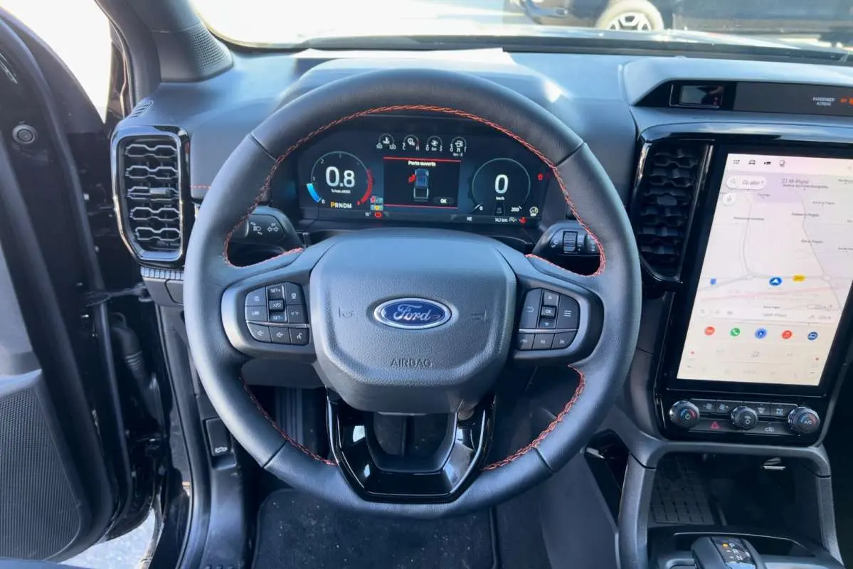 Vue intérieure centrée sur le volant cuir noir avec surpiqûres orange et écran tactile vertical du Ford Ranger 2026.