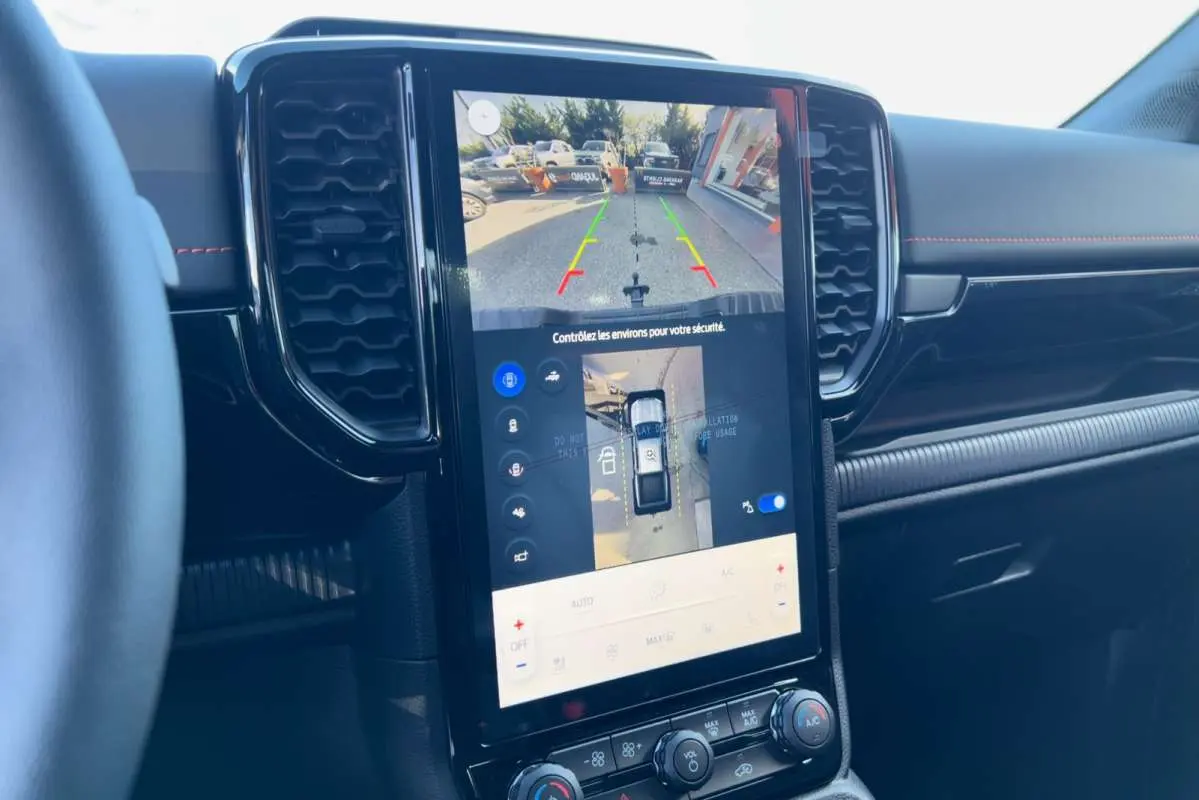 Vue intérieure centrée sur l'écran tactile 12 pouces du Ford Ranger Wildtrak noir agate, affichant la caméra 360° et aides au stationnement.
