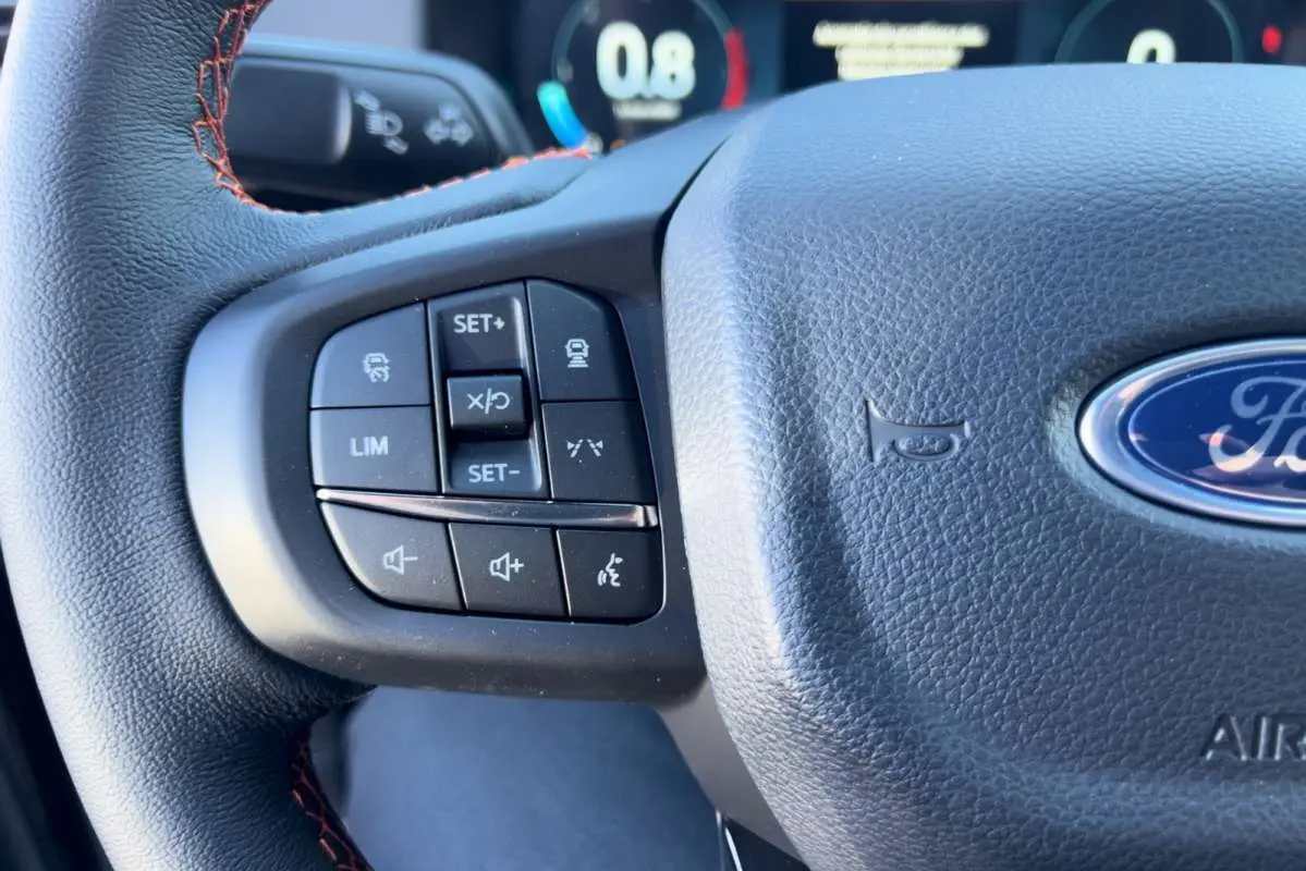 Gros plan sur le volant cuir multifonctions du Ford Ranger Wildtrak 2026 avec commandes intégrées et surpiqûres orange.
