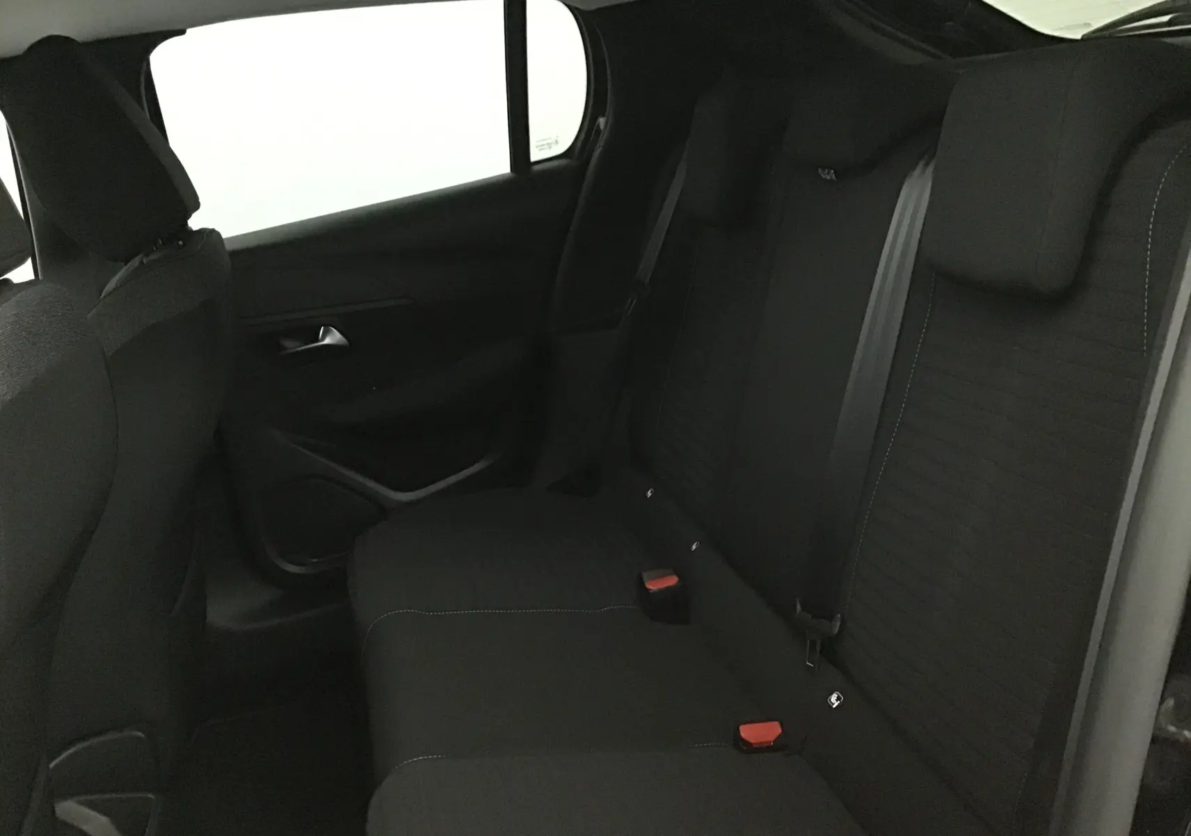 Vue intérieure du siège arrière côté gauche d'une Peugeot 208 noire avec ceintures et appuie-têtes visibles.
