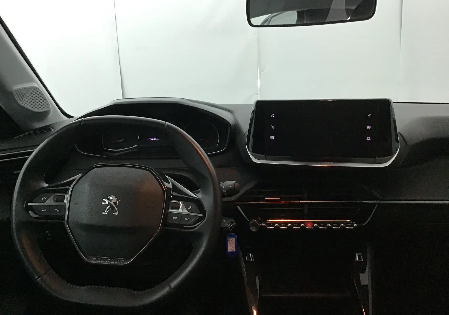 Intérieur de la Peugeot 208 noire 2022, vue du poste de conduite avec volant compact et écran tactile central.