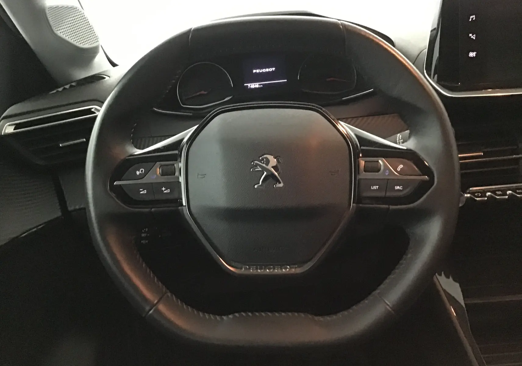 Volant en cuir noir de la Peugeot 208 1.2 PureTech 100 Style, avec commandes intégrées et tableau de bord numérique.