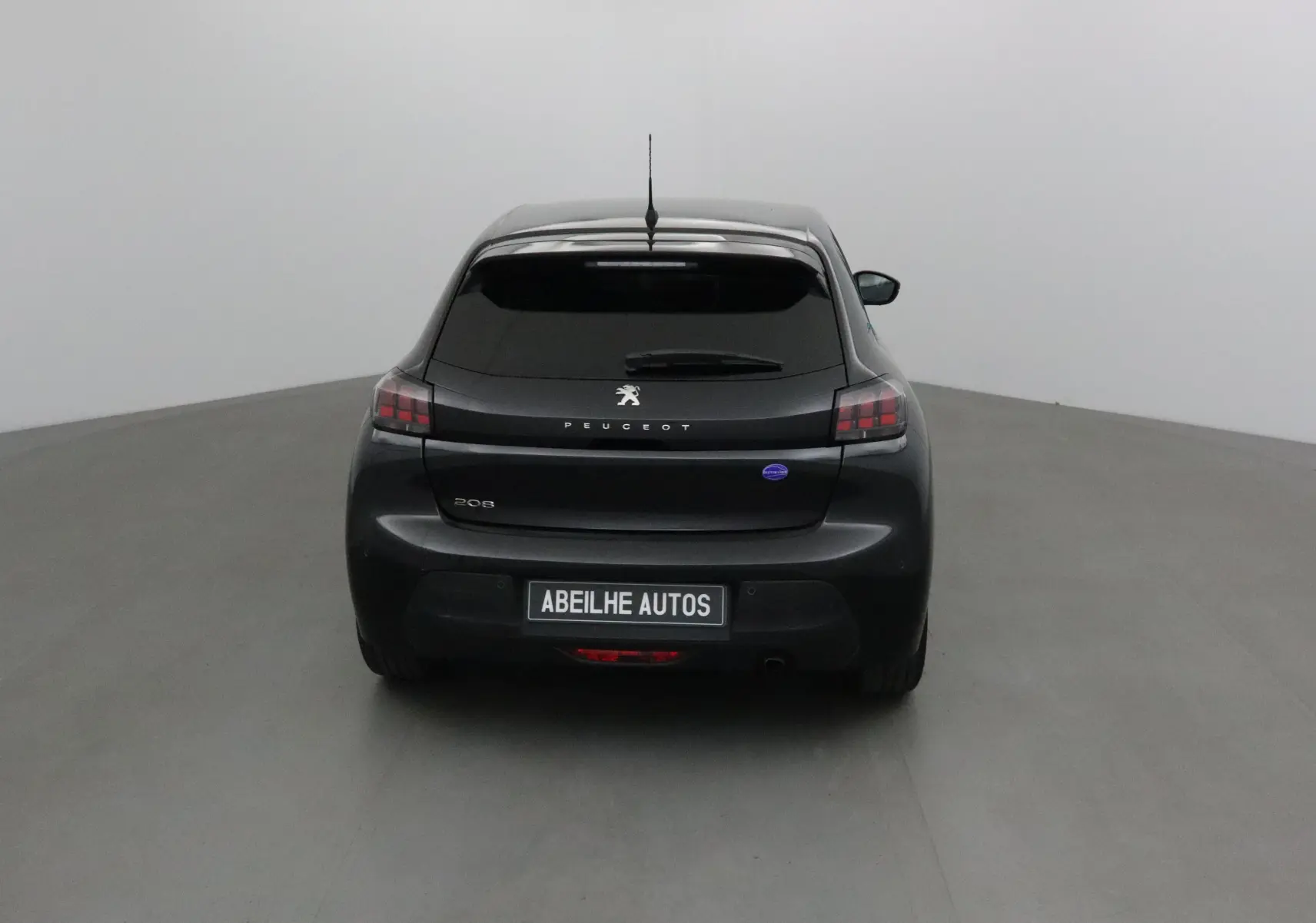 Vue arrière d'une Peugeot 208 noire 2022 avec vitres teintées et logo Peugeot bien visible sur le hayon.