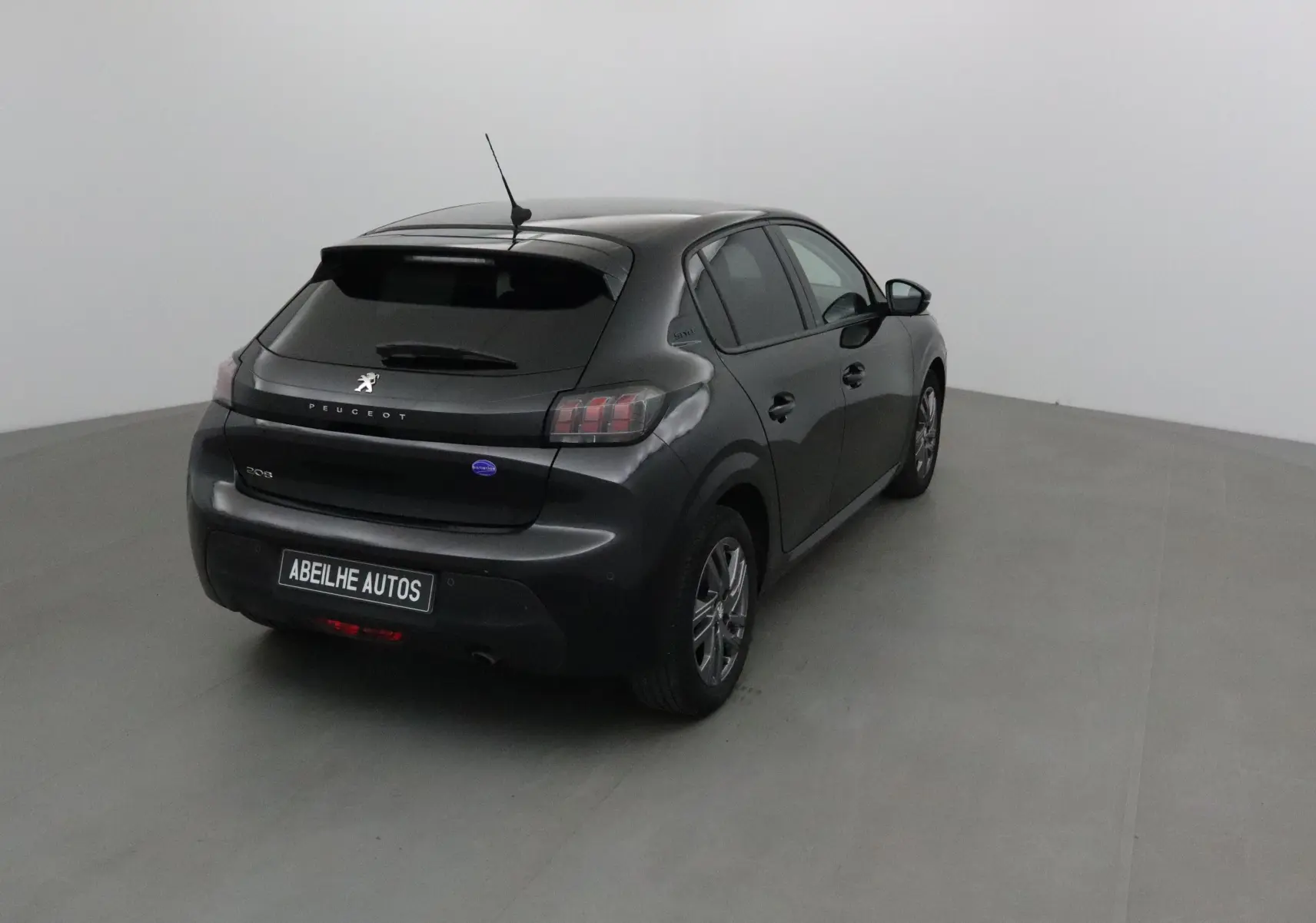 Vue 3/4 arrière droite d'une Peugeot 208 noire 2022 avec feux arrière caractéristiques et antenne sur le toit.