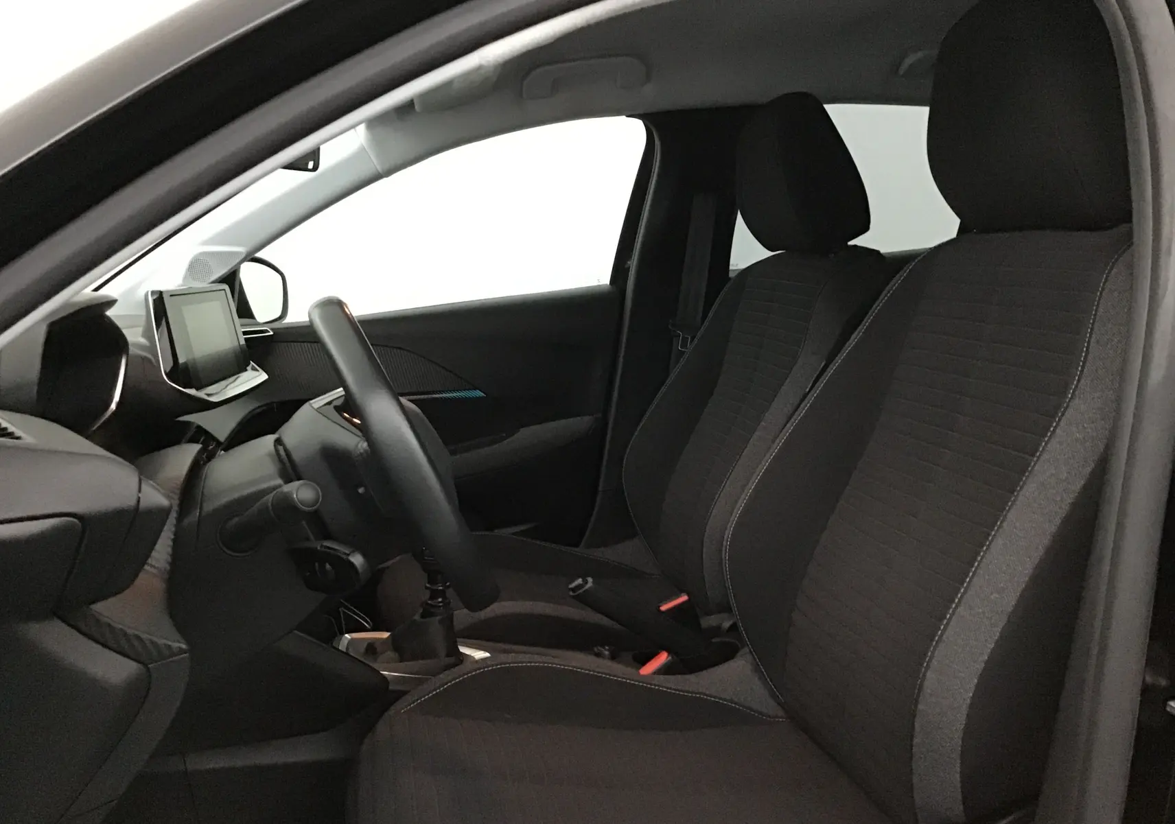 Intérieur avant droit de la Peugeot 208 noire 2022, montrant sièges tissu noir et tableau de bord avec écran tactile.