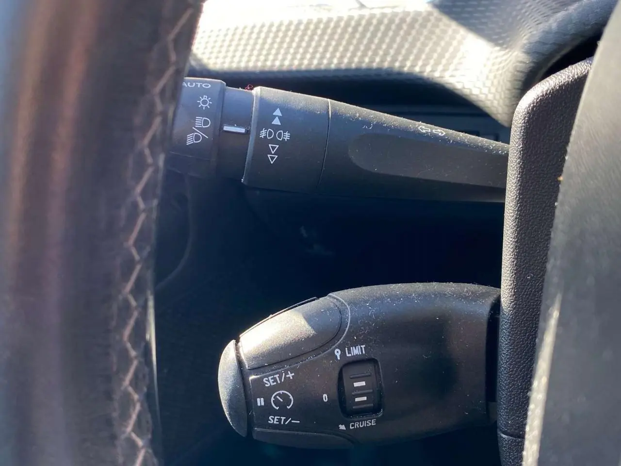 Gros plan sur la commande de régulateur de vitesse au volant cuir noir d'un Peugeot 2008 2019.