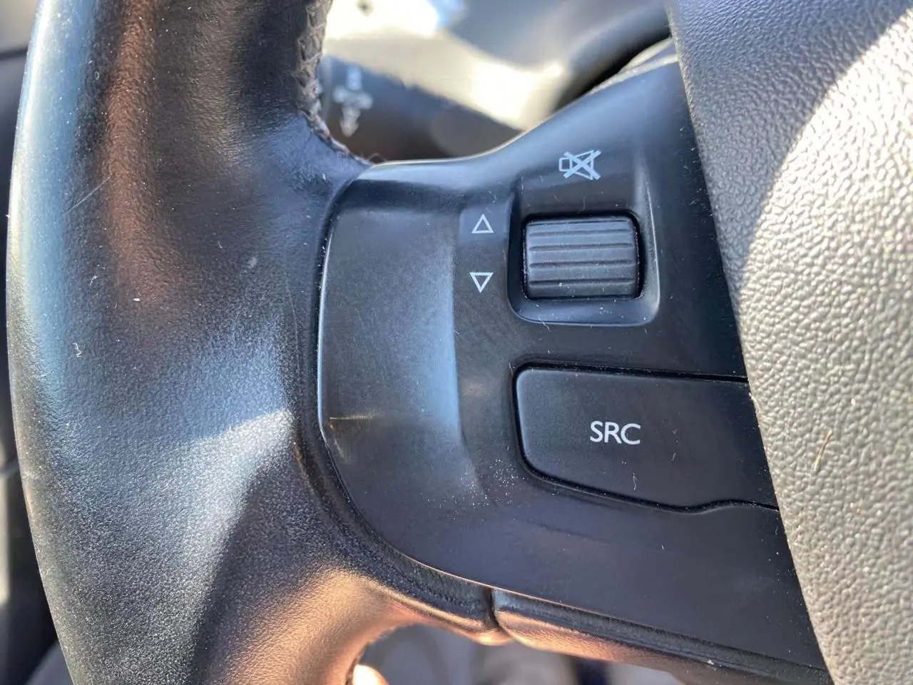 Gros plan sur les commandes audio du volant cuir noir du Peugeot 2008 2019, boutons SRC et volume.