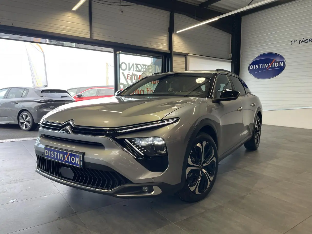 Citroën C5 X gris foncé vue 3/4 avant droit en intérieur, avec calandre distinctive et jantes modernes.