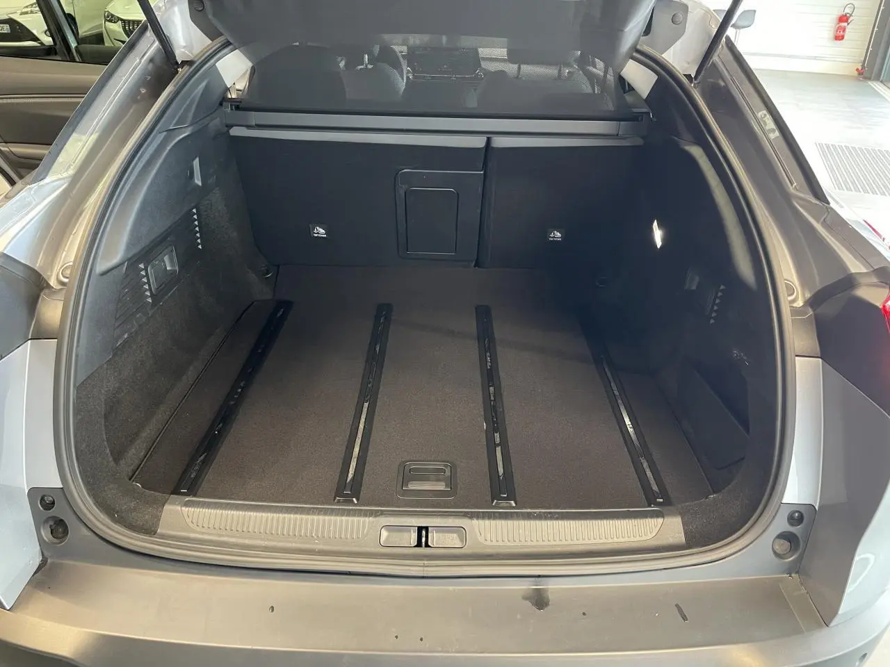 Vue arrière du coffre ouvert d'une Citroën C5 X gris foncé 2024, montrant un espace de chargement spacieux et bien fini.