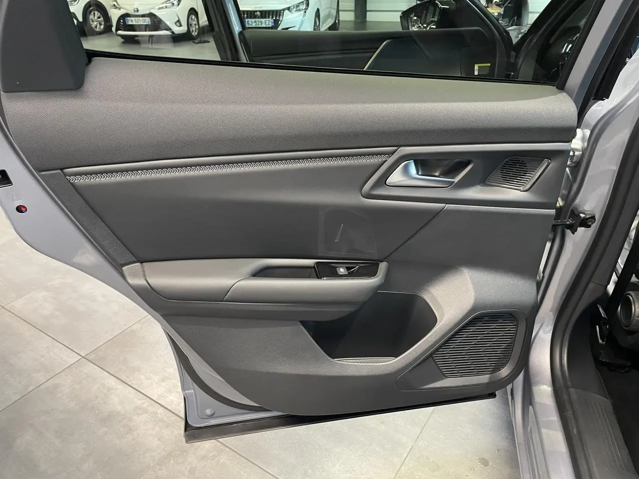 Vue intérieure de la porte avant gauche du Citroën C5 X gris foncé 2024, avec poignée argentée et haut-parleur intégré.