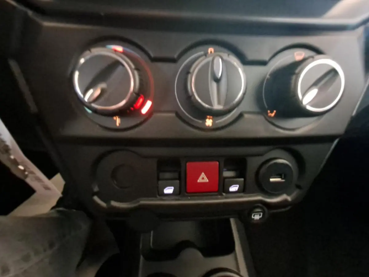 Vue rapprochée des commandes de climatisation et des boutons centraux dans l'habitacle de l'AIXAM AMBITION gris clair 2024.