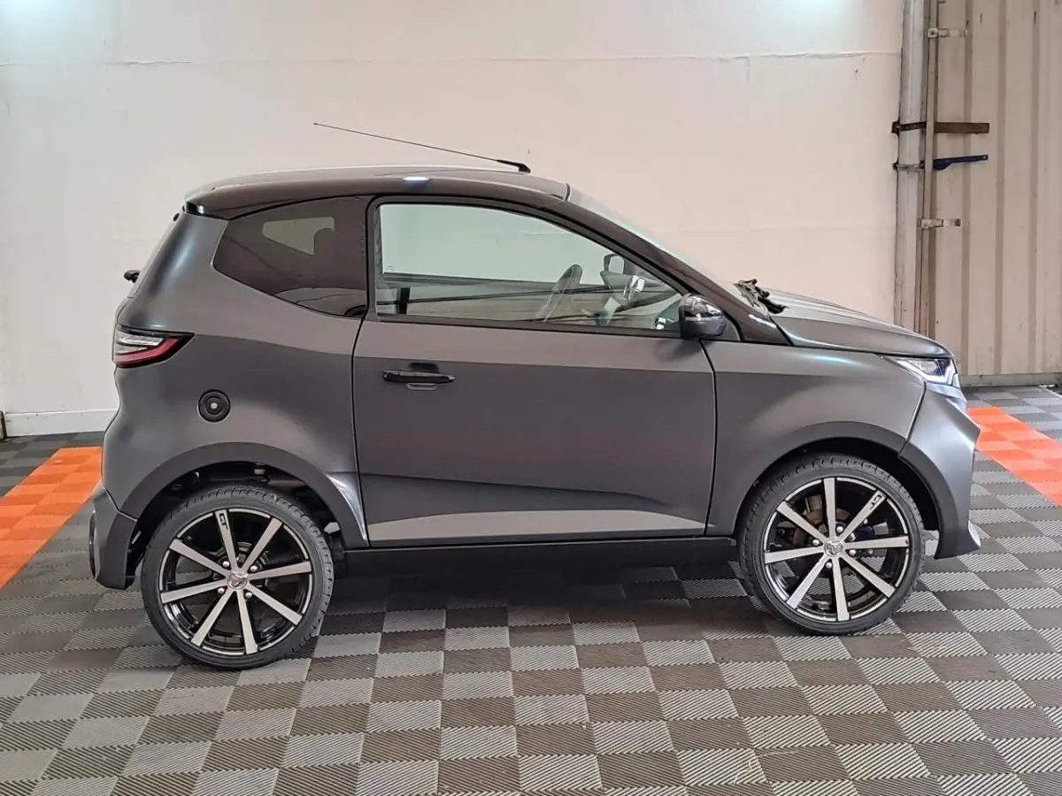 Vue de profil droit d'une Aixam Ambition 2024 gris clair avec jantes alliage noires diamantées et rétroviseurs chromés.