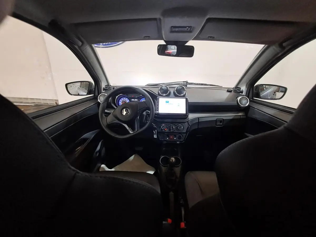 Vue intérieure avant de l'Aixam Ambition 2024, tableau de bord noir avec écran tactile et volant compact.