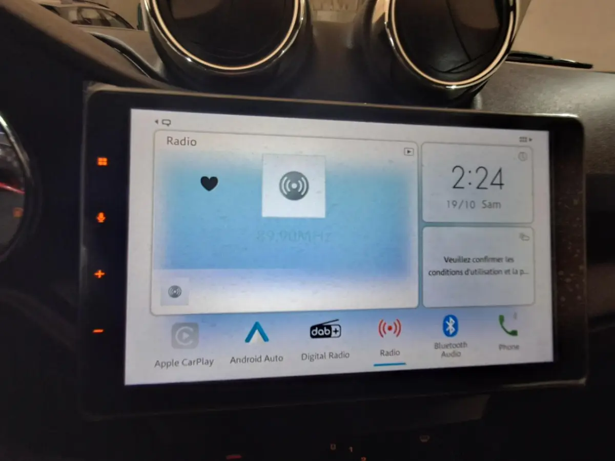 Écran tactile central de l’Aixam Ambition gris clair, affichant les options radio et connectivité, vue de face rapprochée.