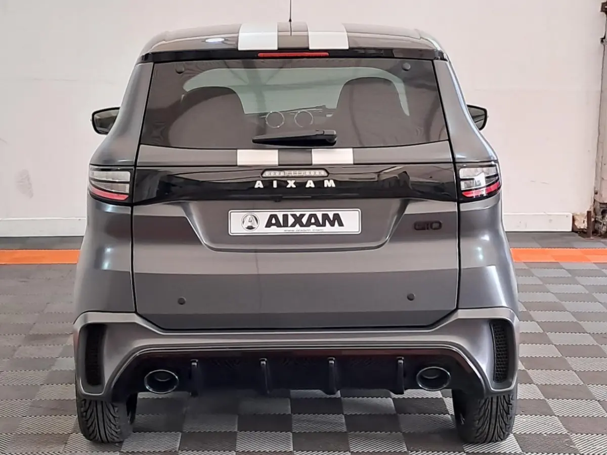 Vue arrière d'une Aixam Ambition gris clair 2024 avec bandes blanches et double sortie d'échappement intégrée.