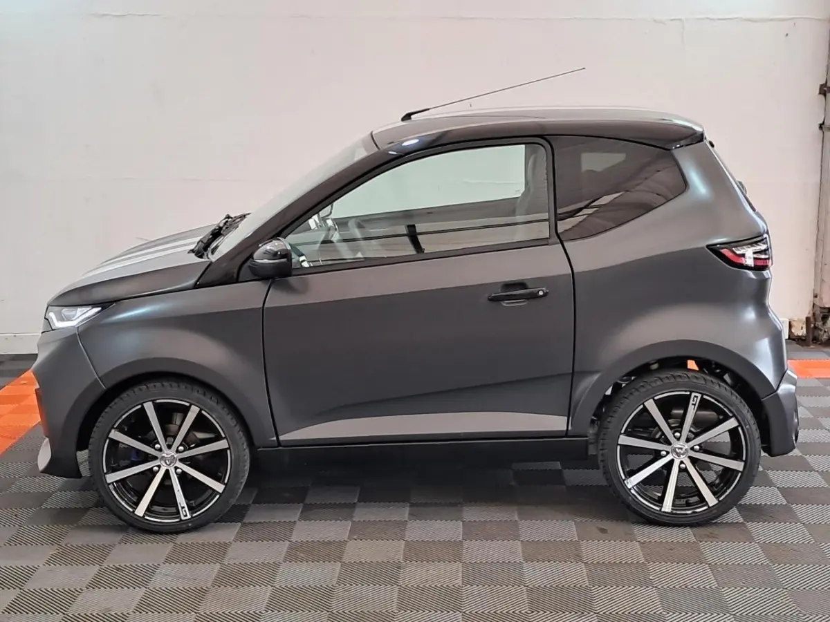 Vue de profil côté gauche de l'Aixam Ambition 2024 gris clair avec jantes alliage noires diamantées et lignes épurées.