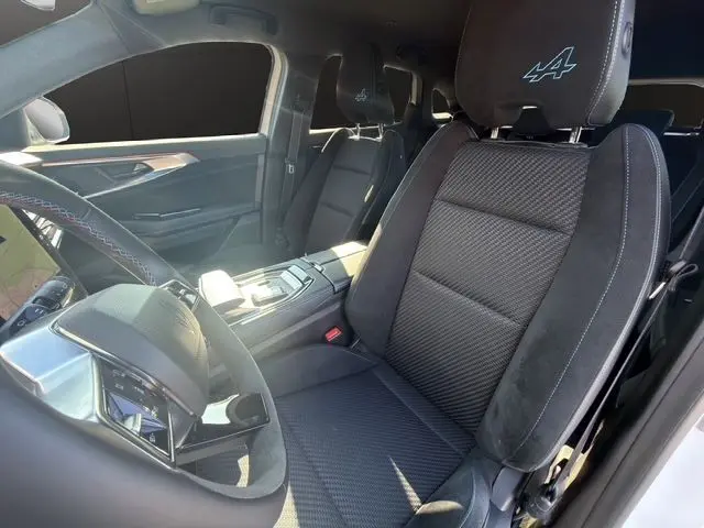 Vue intérieure côté conducteur du Renault Austral 2025, sièges noirs avec logo Alpine brodé sur les appuie-têtes.
