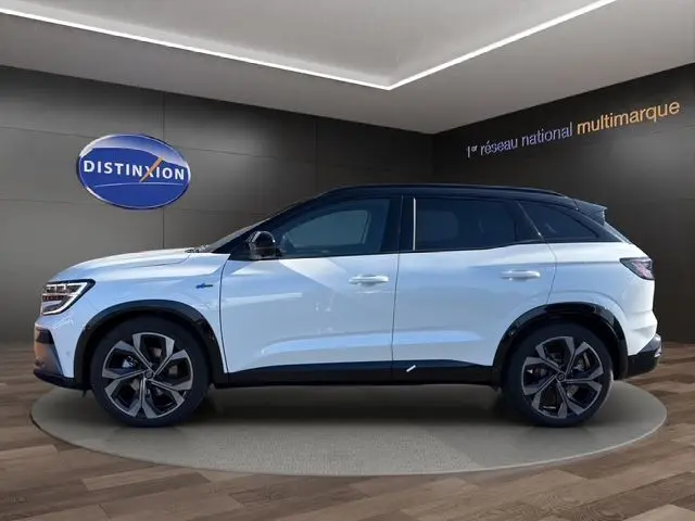 Profil droit du Renault Austral 2025 blanc nacré avec toit noir et jantes distinctives en intérieur showroom.