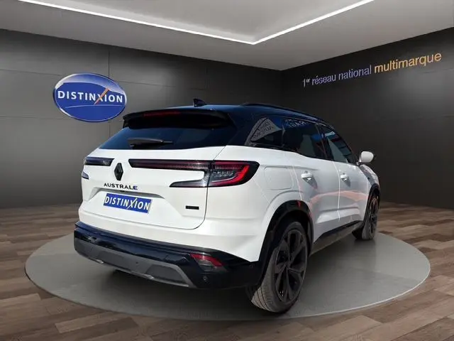 Vue 3/4 arrière droite du Renault Austral blanc nacré avec toit noir et hayon motorisé, en intérieur showroom.