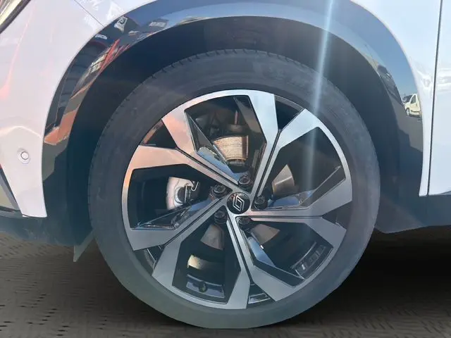 Gros plan sur la roue avant droite du Renault Austral blanc nacré avec jante alliage bicolore et toit noir visible.