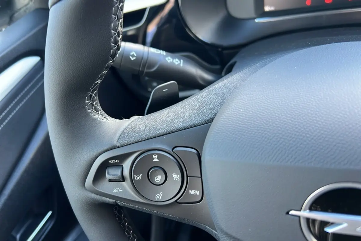Gros plan sur le volant cuir noir de l’Opel Corsa Hybrid 2026, avec commandes multifonctions et bouton de régulateur de vitesse.