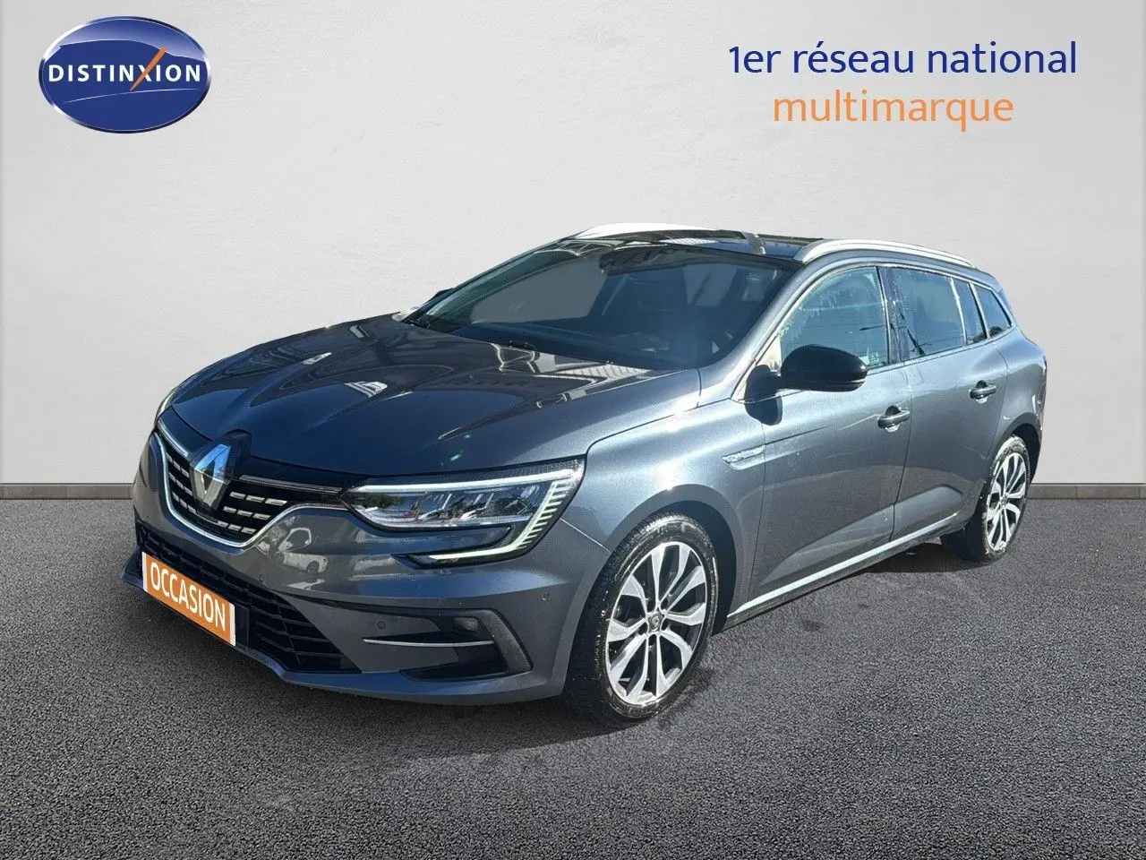 Renault Mégane Break gris titanium métal vue 3/4 avant droit avec jantes bi-ton et feux LED allumés.