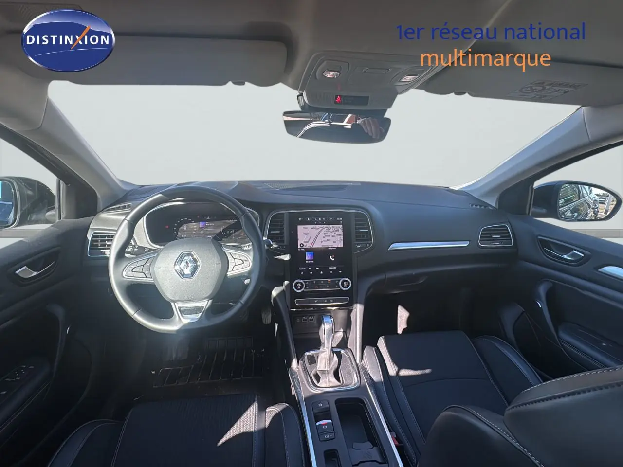 Vue intérieure avant de la Renault Mégane Break 2024, tableau de bord noir avec écran tactile et volant multifonction.