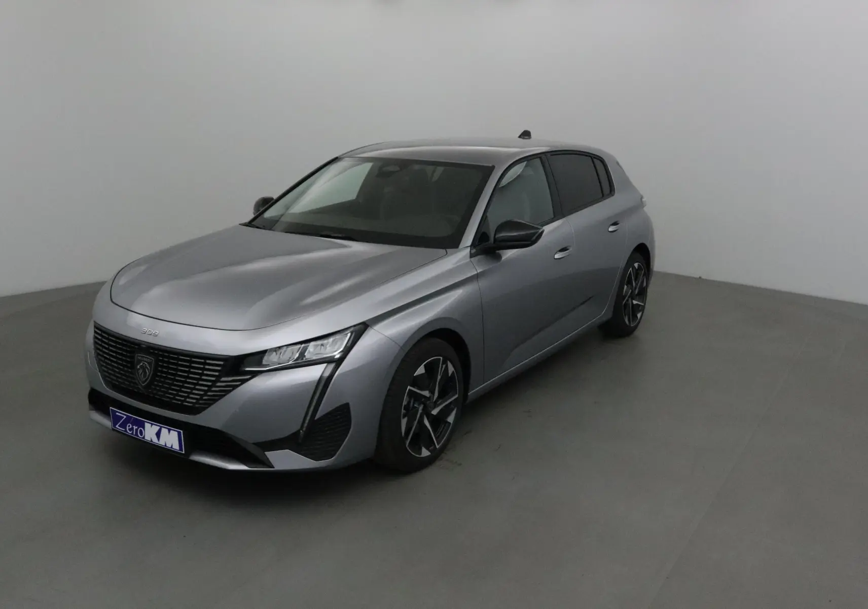 Peugeot 308 gris Artense vue 3/4 avant droit dans un studio, avec calandre noire et jantes alliage.