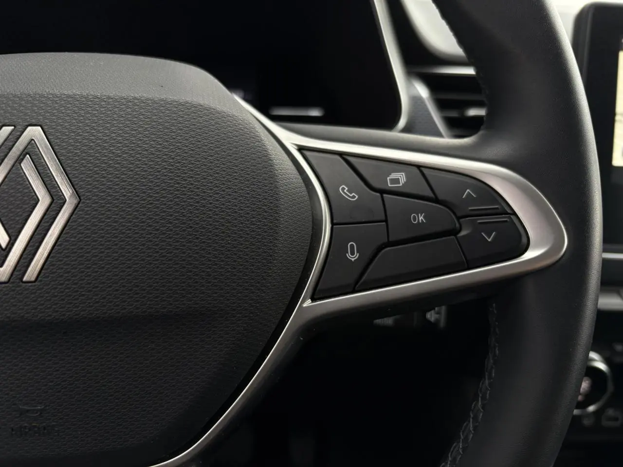 Gros plan sur le volant en textile grainé du Renault Arkana 2025, montrant les commandes multifonctions à droite.