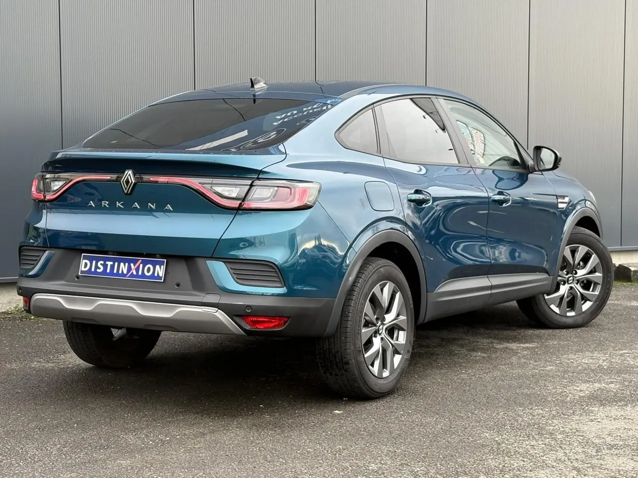 Vue 3/4 arrière droite d’un Renault Arkana bleu Zanzibar avec feux arrière LED et vitres surteintées.