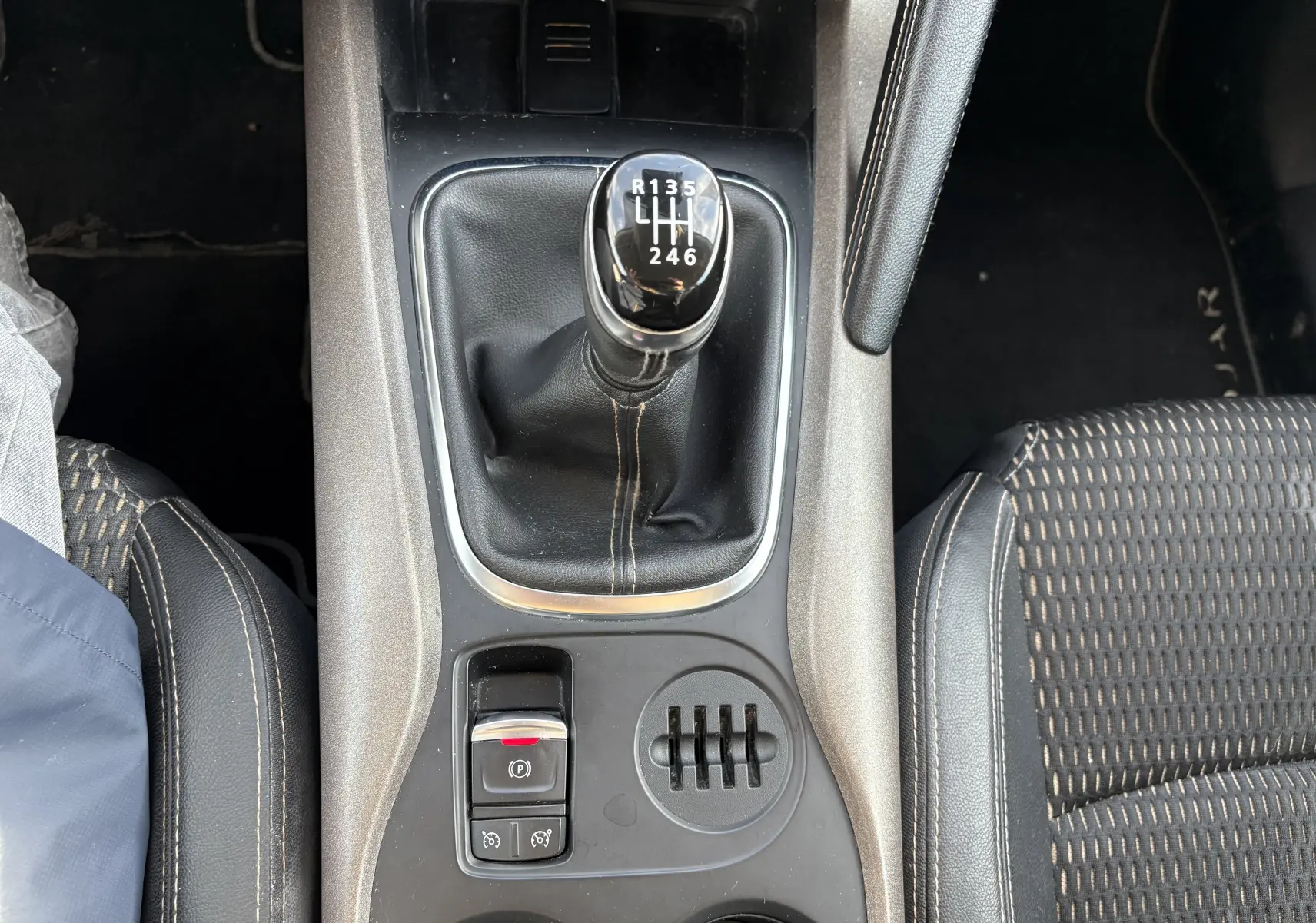 Vue plongeante sur la console centrale du Renault Kadjar 2015, boîte manuelle noire avec levier de vitesses et sièges tissu.