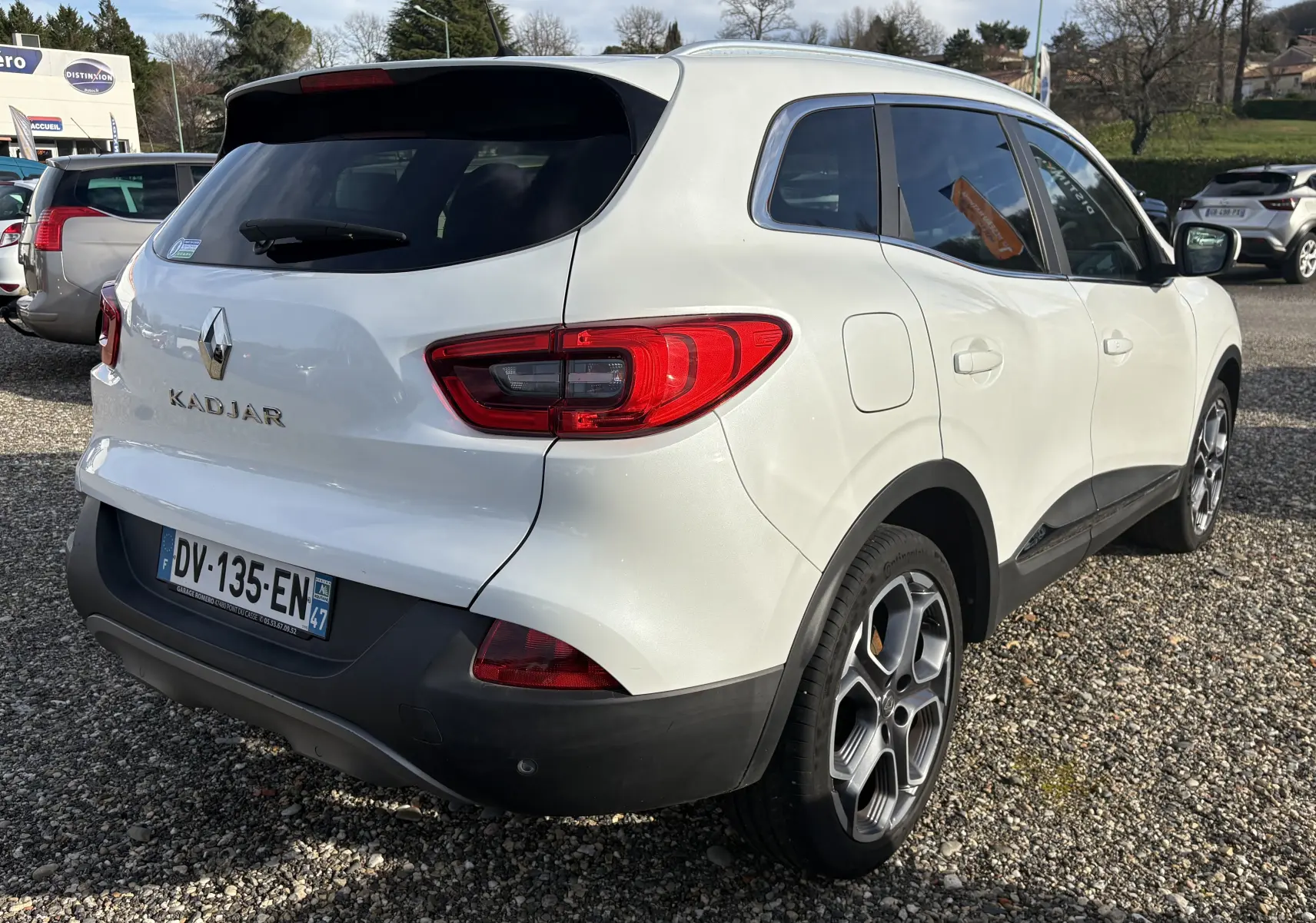 Vue 3/4 arrière droite d'un Renault Kadjar blanc de 2015, avec feux arrière rouges et jantes alliage distinctives.