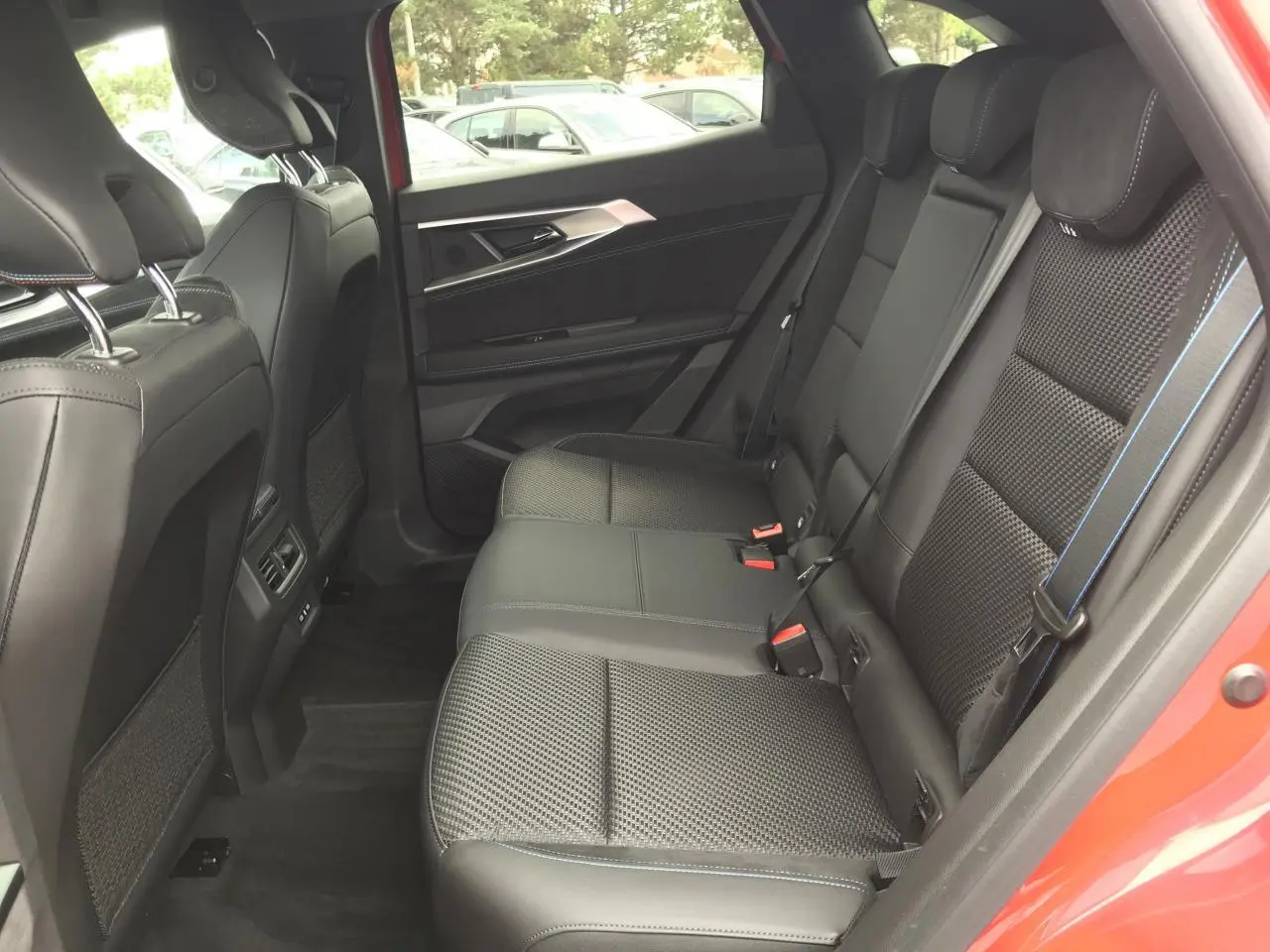 Vue intérieure côté droit des sièges arrière en cuir noir avec surpiqûres bleues du Renault Austral Esprit Alpine rouge et noir.