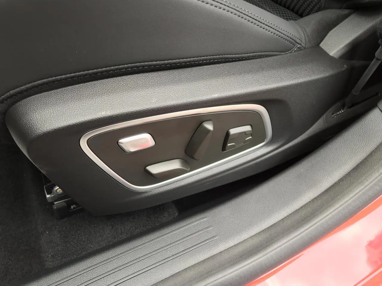 Gros plan sur les commandes de réglage électrique du siège conducteur noir du Renault Austral rouge et noir, côté gauche.